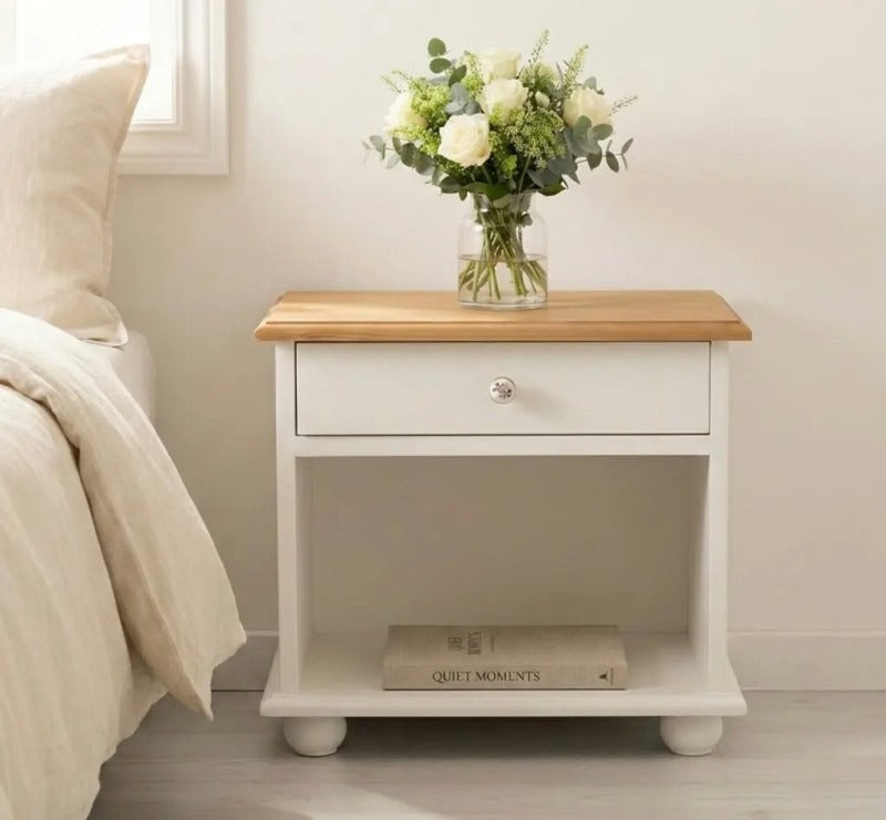 Table de chevet en pin massif avec un tiroir et une niche ouverte, présentée dans une chambre.