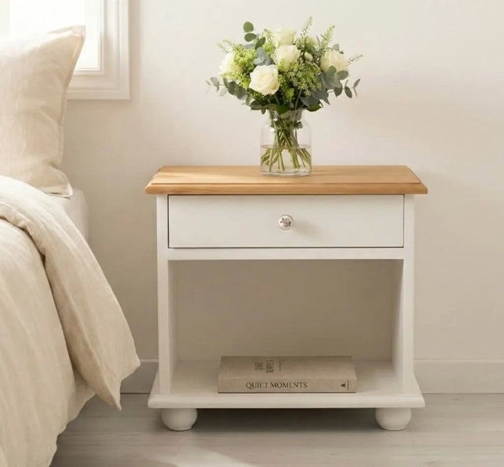 Table de chevet en pin massif avec un tiroir et une niche ouverte, présentée dans une chambre.