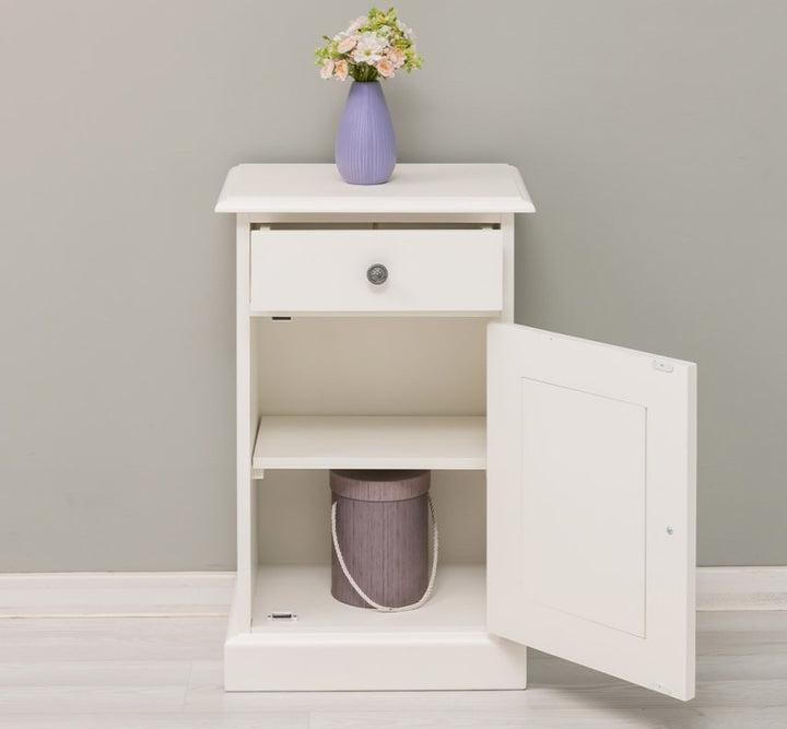 Table de chevet en pin massif finition blanche avec porte ouverte montrant l’espace de rangement intérieur.
