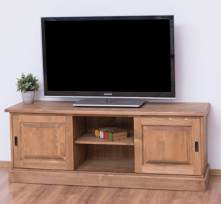 Meuble TV en pin massif finition bois naturel avec 2 portes coulissantes et niche centrale avec étagère intérieure, avec téléviseur posé dessus.  
