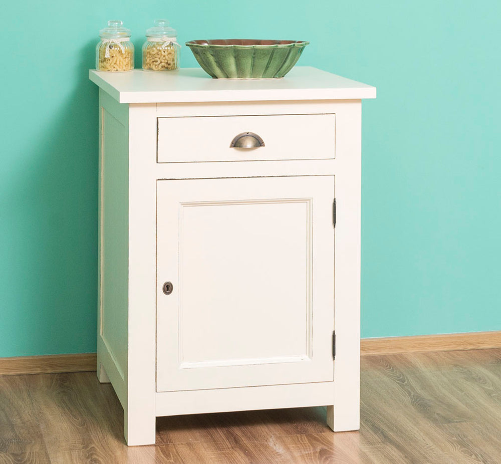 Meuble bas entièrement blanc avec un tiroir et une porte fermée, posé dans une cuisine devant un mur bleu turquoise avec des pots de pâtes sur le dessus.