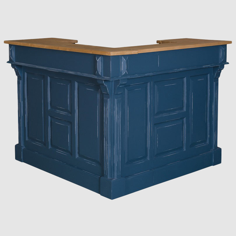 Vue en angle extérieur d’un bar en configuration d’angle, avec façades pleines à panneaux moulurés et plateau supérieur en bois