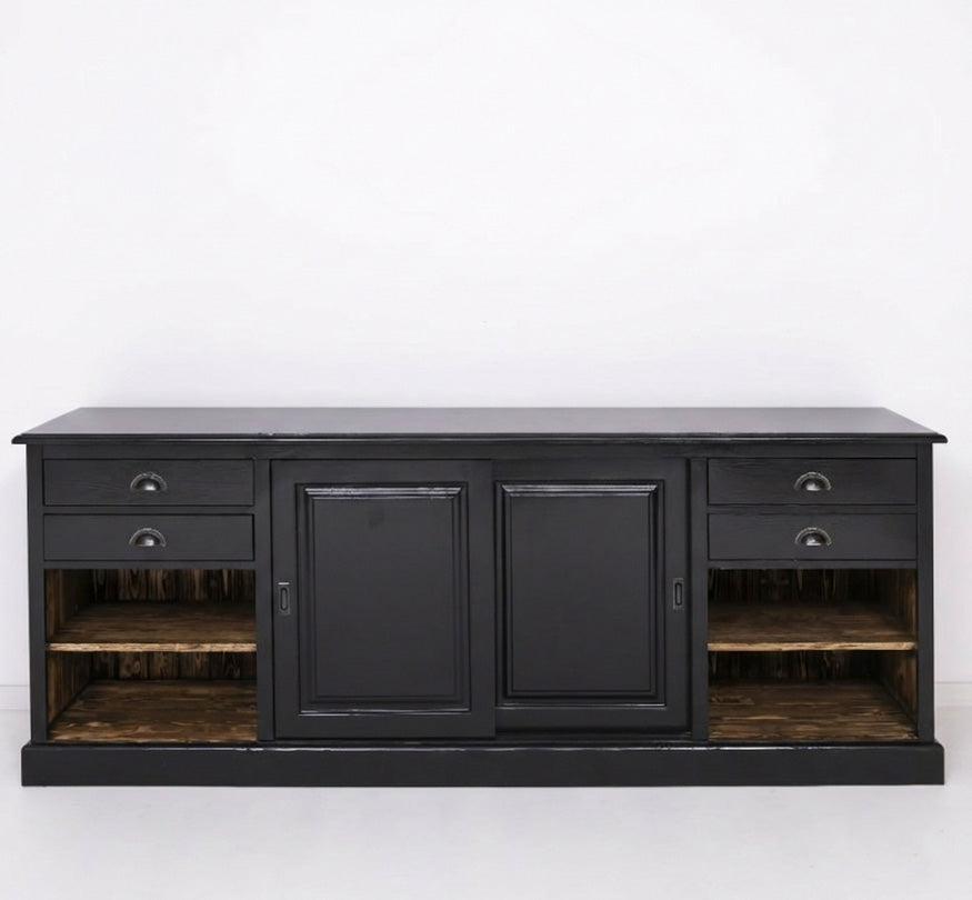 Buffet bas en bois peint noir vu de face avec deux portes centrales pleines, deux tiroirs de chaque côté en partie haute et deux niches ouvertes latérales laissant apparaître des étagères intérieures en bois.