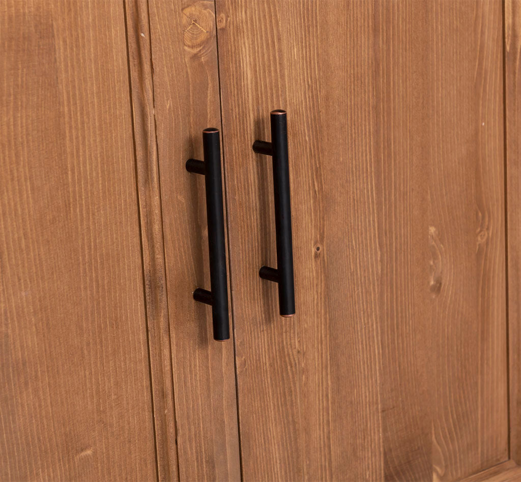 Détail des poignées métalliques sur les portes d’une colonne de cuisine en pin massif.