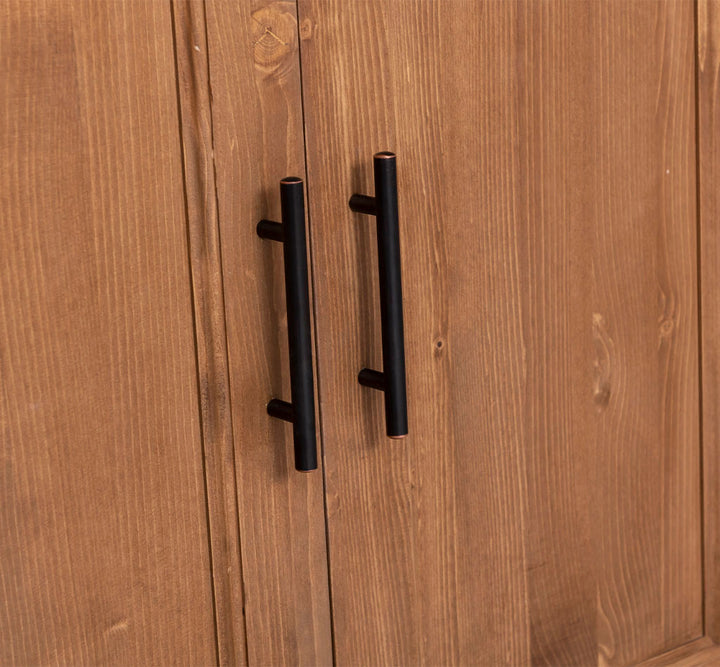 Détail des poignées métalliques sur les portes d’une colonne de cuisine en pin massif.