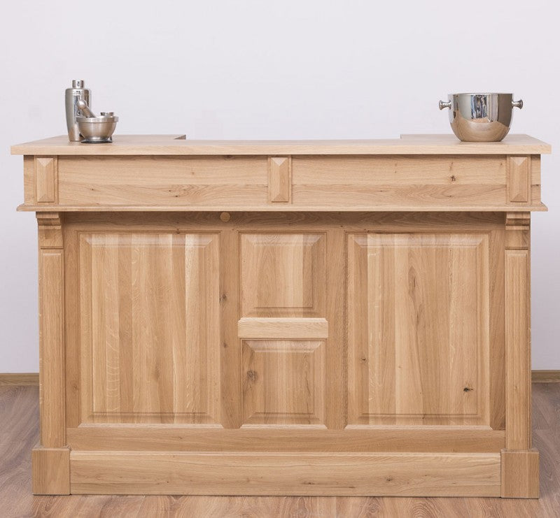 Vue de face d’un bar en chêne avec façade à panneaux et plateau supérieur, présenté en situation avec accessoires posés