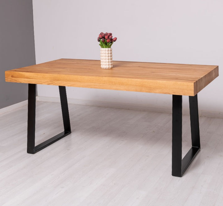 Vue d’ensemble de la table en chêne massif avec pied central en métal noir sur sol clair.
