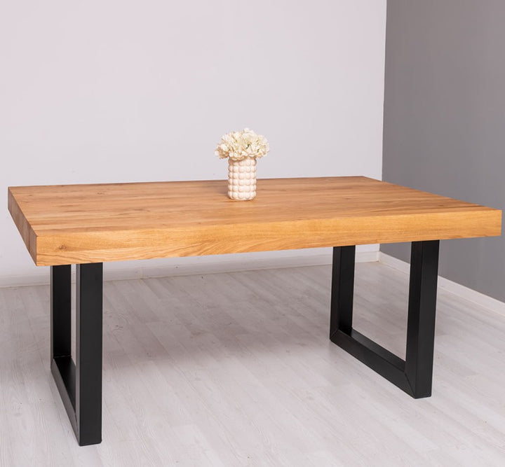 Vue frontale de la table en chêne massif avec plateau épais et pieds en métal noir.
