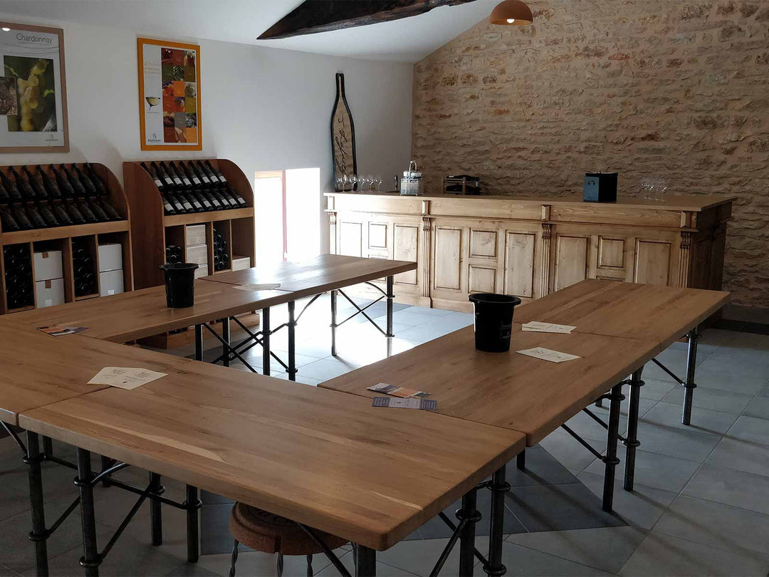 Aménagement de cave de dégustation avec bar comptoir et grandes tables en bois