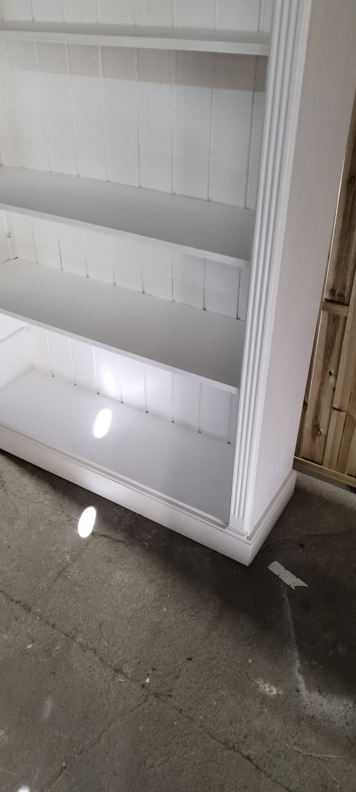 Bibliothèque ouverte blanche, détail du bas : étagères et socle mouluré