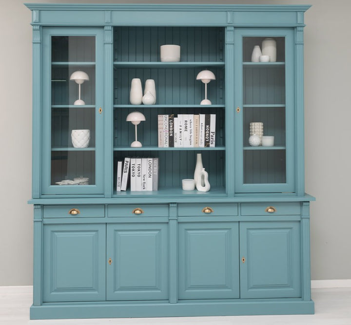 Vue frontale d’une bibliothèque en pin massif style Directoire bleue avec étagères ouvertes et portes vitrées latérales