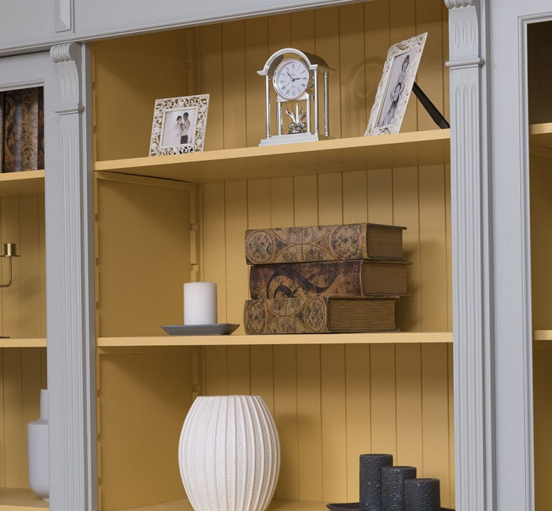 Détail des étagères ouvertes avec intérieur jaune dans une bibliothèque en pin massif style Directoire