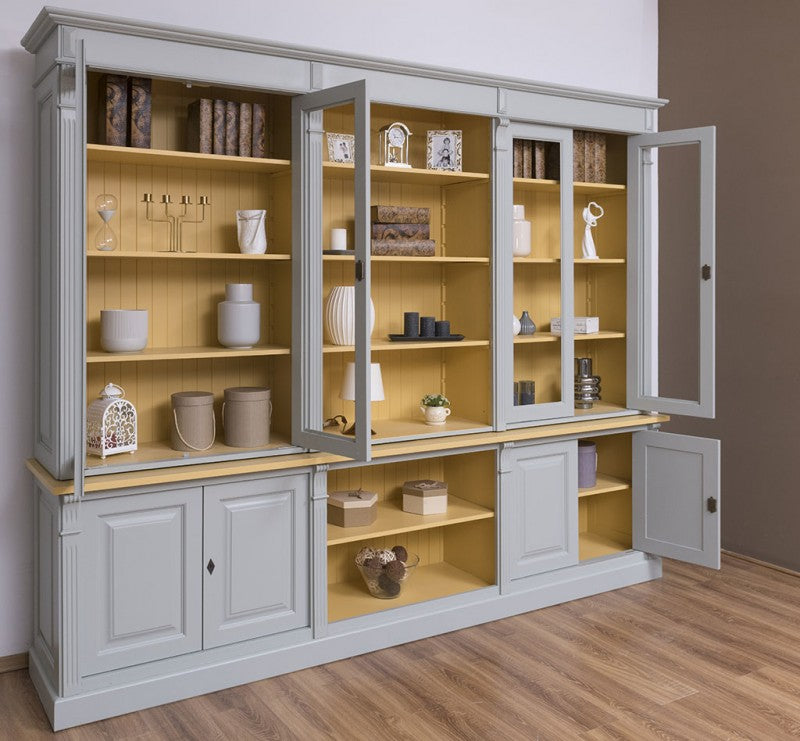 Bibliothèque en pin massif style Directoire gris clair avec portes vitrées ouvertes, intérieur jaune et rangements bas ouverts
