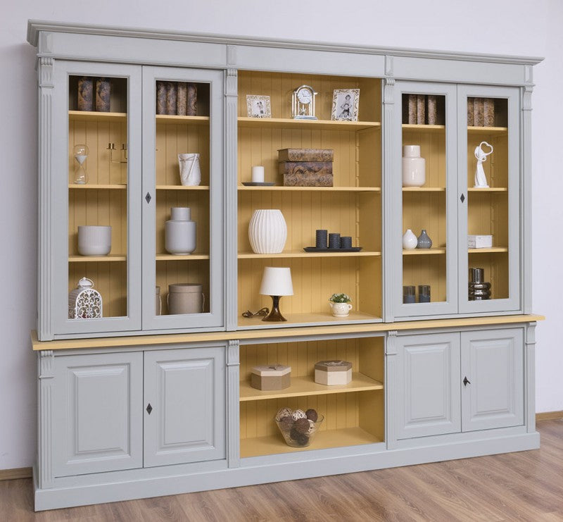 Vue frontale d’une bibliothèque en pin massif style Directoire gris clair avec portes vitrées fermées et niche centrale ouverte