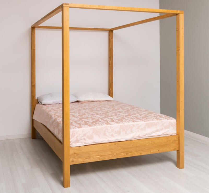 Lit à baldaquin en pin massif vue de profil dans une chambre — Le Grenier Campagnard