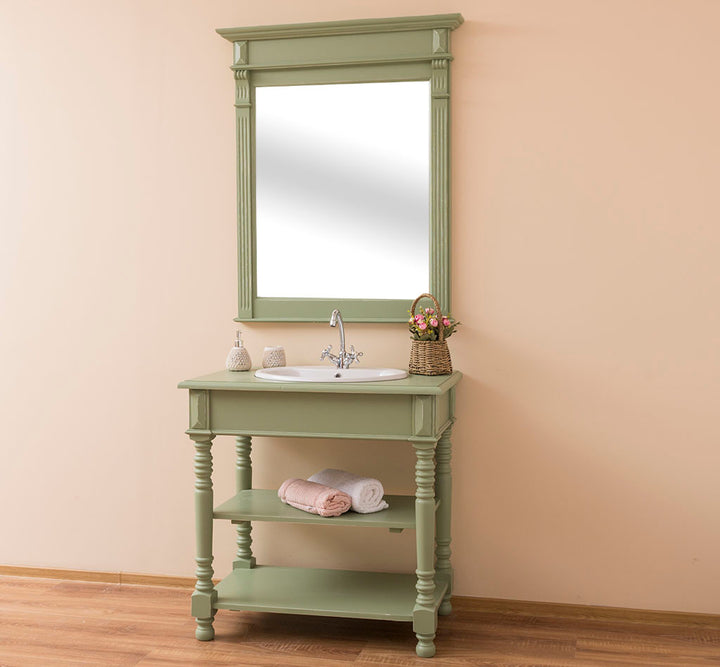 Meuble lave-mains en bois peint vert sauge avec vasque encastrée et grand miroir assorti dans une salle de bain style rustique chic.