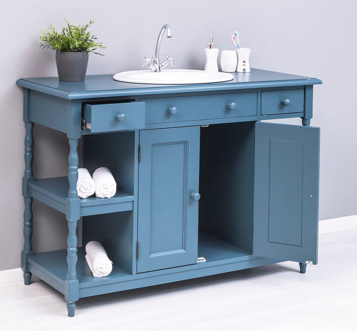 Meuble vasque bleu canard avec rangements ouverts et tiroirs pour une salle de bain style maison de campagne.