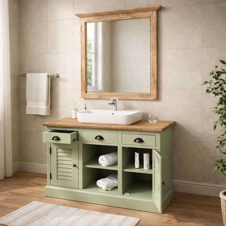 Meuble de salle de bain de style champetre en bois peint en vert pastel avec vasque blanche et grand miroir en bois vieilli.
