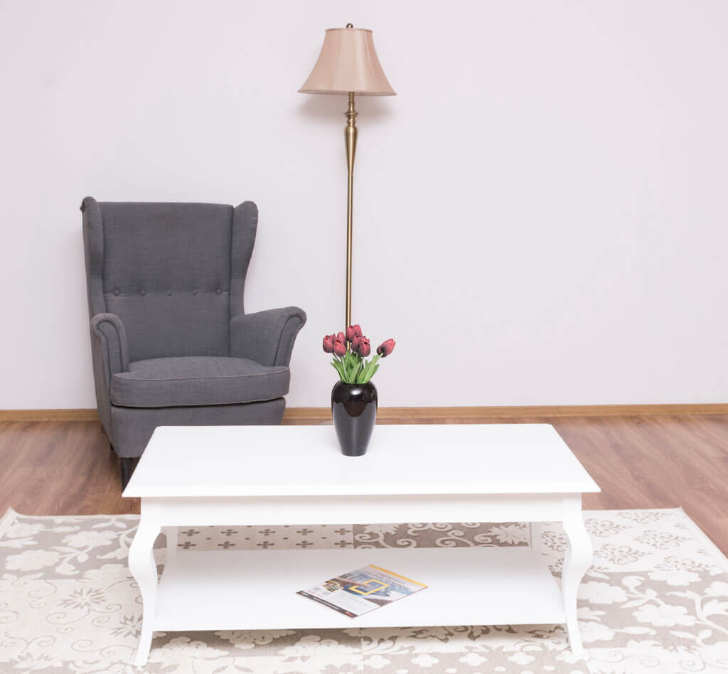 Table basse entièrement blanche avec pieds galbés et étagère de rangement dans un salon décor champêtre.
