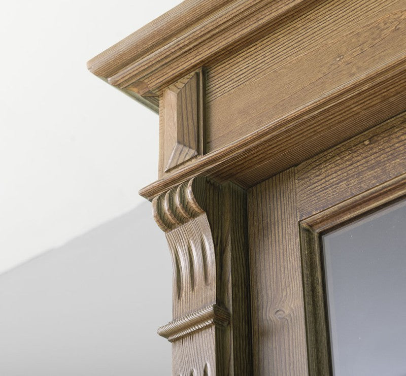 Détail du montant et des moulures de la partie haute d’une vitrine en pin massif.