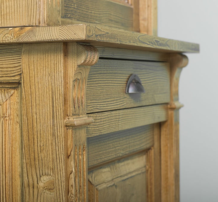 Détail du tiroir et de la poignée en métal sur une vitrine en pin massif.
